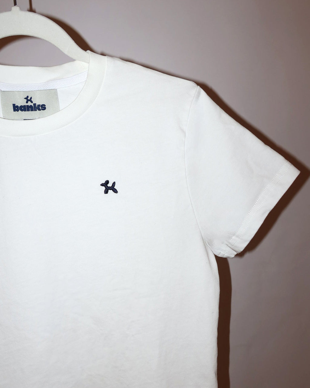 White t-shirt with a logo on a hanger against a plain background